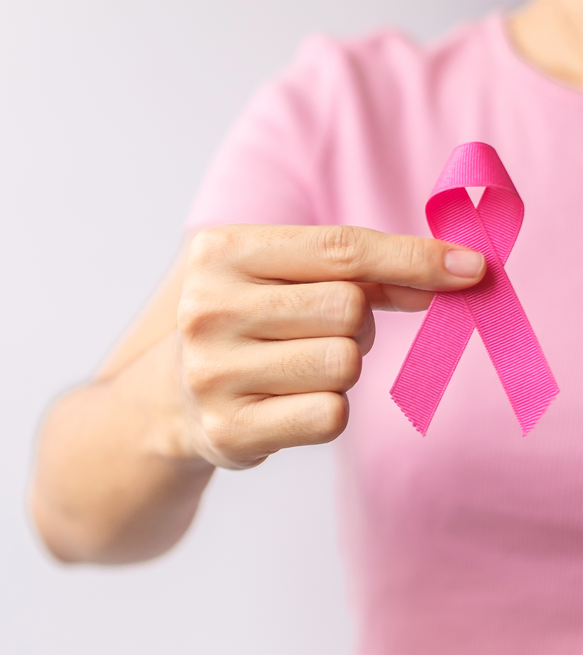 hand holding a pink ribbon for breast cancer awareness
