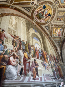 Interior view of a grand fresco depicting philosophers and scholars in discussion beneath ornate golden ceilings, showcasing Renaissance artistry and architectural detail.
