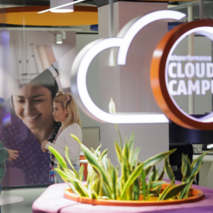 employees talking inside the TP Cloud Campus, with a large illuminated cloud-shaped logo and plants in the foreground.