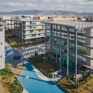 Aerial view of the TP Premises in Moschato, Greece campus with modern office buildings, landscaped walkways, and mountains in the background.