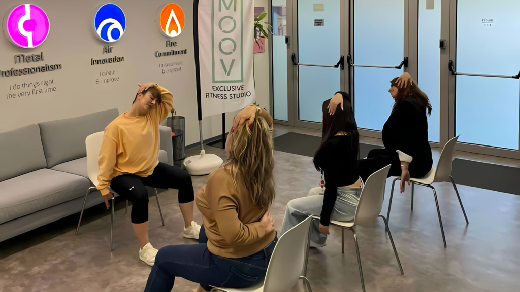 A group of TP Employees participating in a seated stretching session at a fitness studio, guided by an instructor during Health Week 2025.